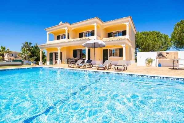 A two-story house with a swimming pool, outdoor seating, and a patio area.