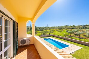 A balcony with a pool, a view of a vineyard, and a tiled floor.