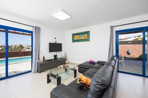 Un salon moderne avec un grand canapé, une table basse en verre et un téléviseur à écran plat.