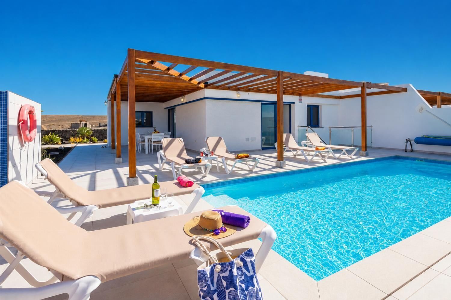 Ein Poolbereich auf dem Dach mit Liegestühlen, einer Pergola und freiem Blick auf die Landschaft.