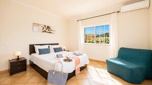 Una camera da letto con un letto, un comodino, una sedia, una finestra vista e un condizionatore d'aria.