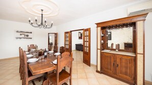 Zona pranzo con tavolo in legno apparecchiato per sei persone, un lampadario e un armadio in legno con specchio e ripiani.