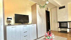 A modern living room with a flat-screen TV, a wooden coffee table with a floral arrangement, and a fireplace.