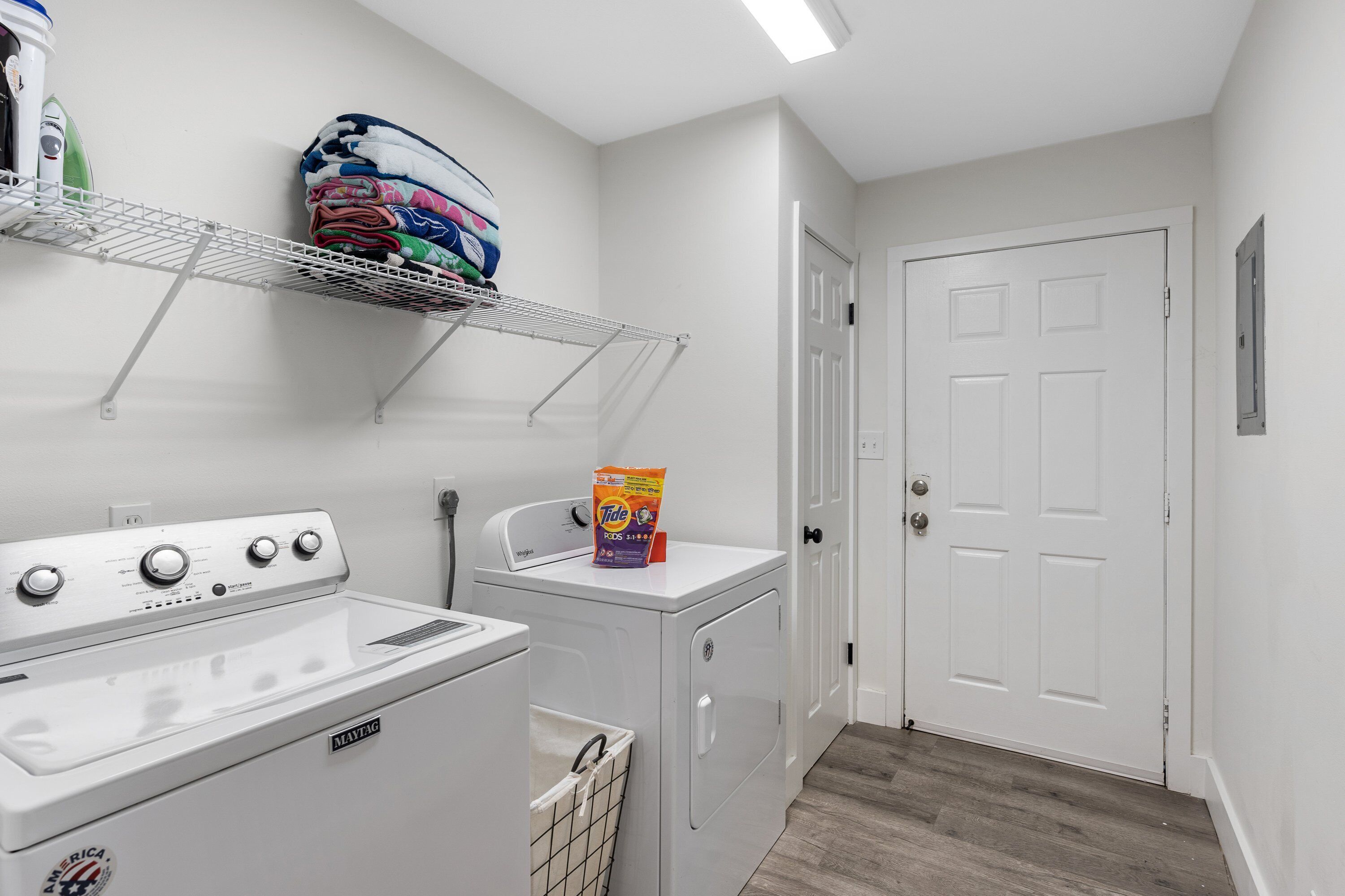 A laundry room with a washing machine, dryer, and stacked laundry on a shelf.
