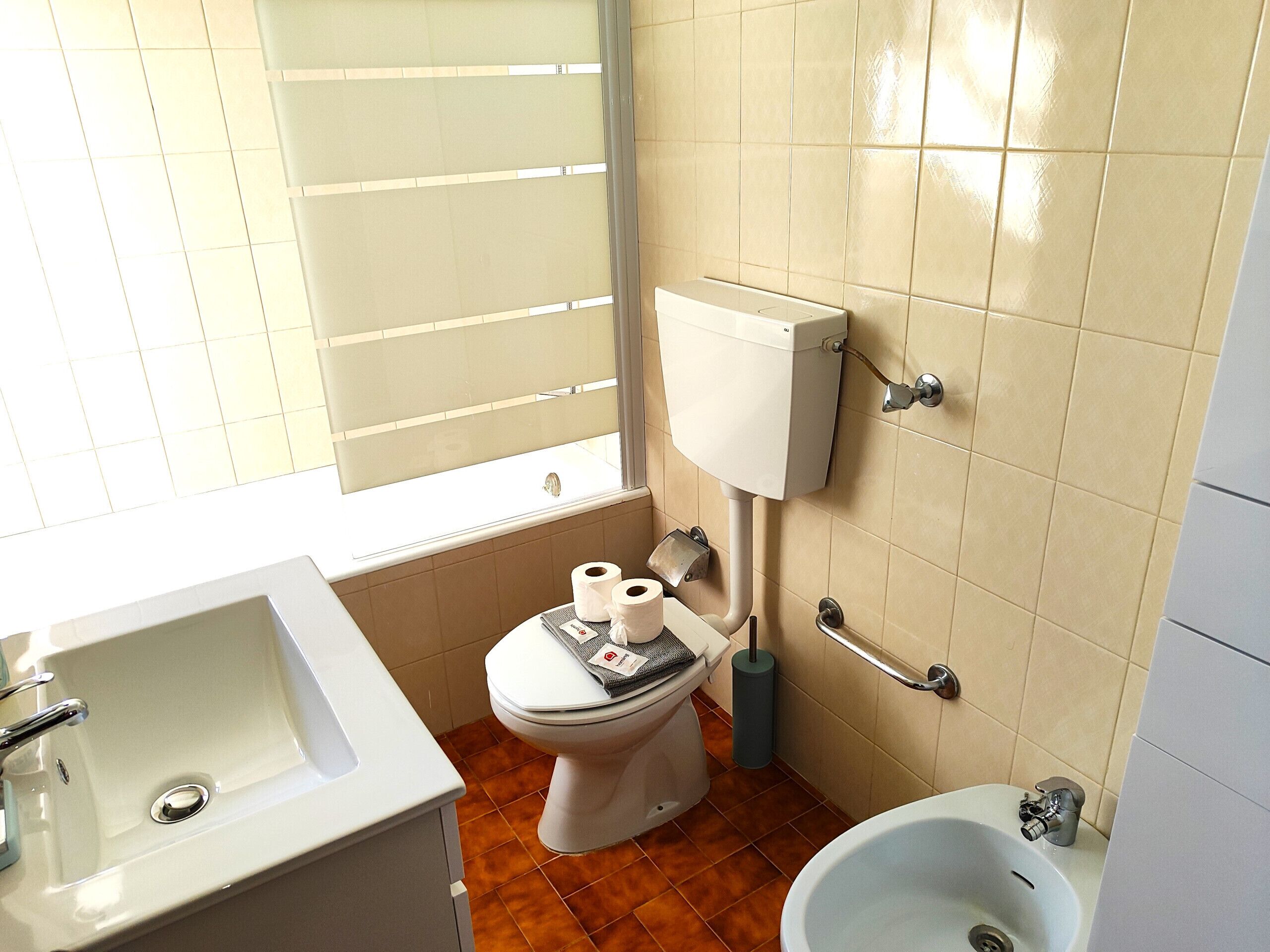 A bathroom with a toilet, sink, and bidet.