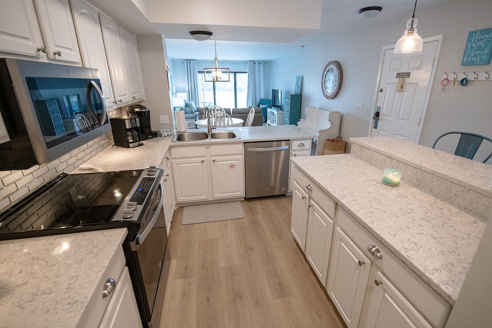 A modern kitchen with white cabinets, stainless steel appliances, and a marble countertop.