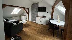 A loft-style room with a dining area, kitchenette, and a TV mounted on the wall.