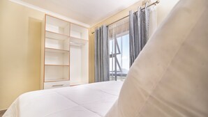 Una camera da letto con un letto, un armadio e una finestra con tende.
