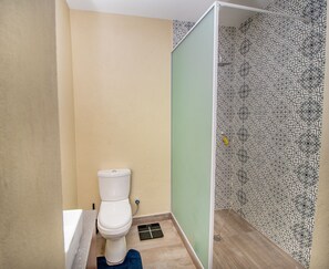 A bathroom with a toilet, a shower, and a patterned wall. - Oh wine at Lucas place (Blantyre)