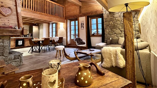 Un interior rústico con chimenea de piedra, muebles de madera y un techo alto con vigas a la vista.