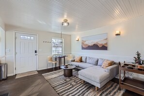 A modern living room with a gray sectional sofa, a round coffee table, and a dining area with a small table and chairs. - Cozy Golden home only one block from all the action, walk to everything! (Golden)