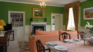 A dining room with a table set for four, a fireplace, a bookshelf, and a green wall. - 2 bedroom accommodation in Broughton, near Skipton (Broughton, near Skipton)
