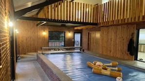 A spacious indoor area with a pool, wooden walls, and a bench. - Quelque Part au Calme (Beaumé)