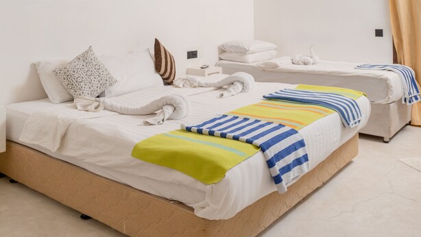 Ein Schlafzimmer mit schrägen Wänden, einem Bett mit vielen Kissen und Decken sowie einem kleinen Nachttisch.