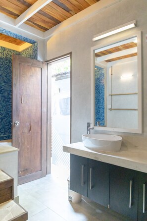 Features a large mirror, white sink, and blue mosaic tile walls.