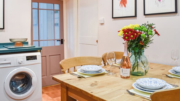 A dining table set with plates, a vase of flowers, and a bottle of wine. - 2 bedroom accommodation in Burrow, near Kirkby Londsdale (Burrow, near Kirkby Londsdale)