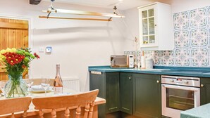 A kitchen with wooden cabinets, a microwave, an oven, and a dining table set with chairs. - 2 bedroom accommodation in Burrow, near Kirkby Londsdale (Burrow, near Kirkby Londsdale)