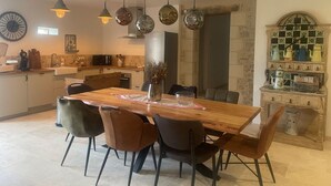 Une cuisine moderne avec une table à manger en bois, des luminaires suspendus et un pare-feu en pierre.