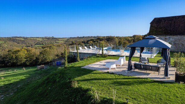 Un espace aménagé au bord de la piscine, avec des chaises longues, un gazebo et une vue sur le paysage environnant.
