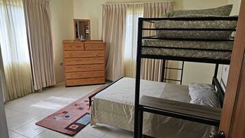 Una habitación con una cama litera, un aparador de madera, un espejo y un tapete estampado.