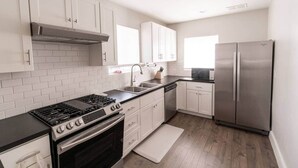 A modern kitchen with white cabinetry, a stainless steel refrigerator, a gas stove, and a microwave.