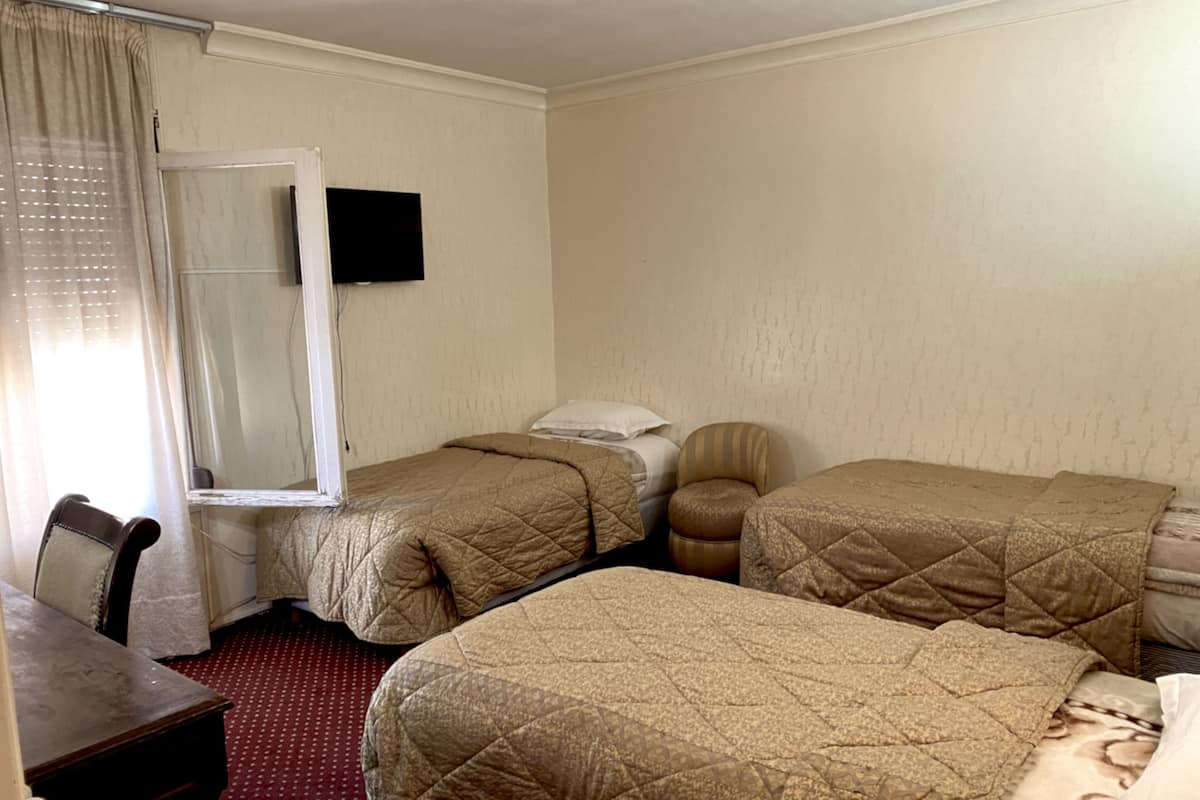 A hotel room with two beds, a desk, and a chair.