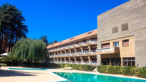 A hotel with a pool, multiple balconies, and a brick facade. - Hôtel Tidghine (Issaguen)