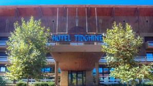 A hotel with a prominent sign reading "HOTEL TIDGINE" and a modern architectural design with a central atrium. - Hôtel Tidghine (Issaguen)