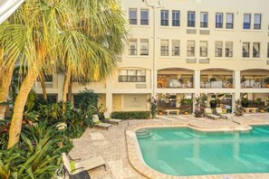 A hotel with a swimming pool, palm trees, and a multi-story building with balconies. - Bliss 1br/Pool/StepsToBeach/Dine (Palm Beach)