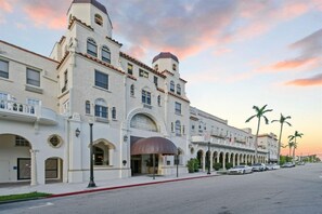 A large, historic building with multiple stories, arched windows, and a prominent entrance with a covered area.