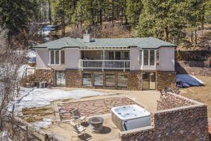A two-story house with a stone exterior, a balcony, and a hot tub in the backyard. - Stone Statesroom (Cascade)