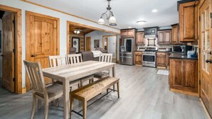 A spacious kitchen with wooden cabinets, a dining table, and modern appliances. - Life on the River at the Cabin (Ellijay)
