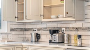 A kitchen with white cabinets, a coffee maker, a toaster, and a bottle of kosher salt.