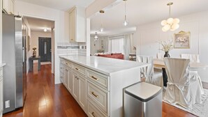 A spacious kitchen with white cabinetry, a marble island, and stainless steel appliances.