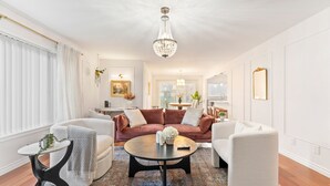 A modern living room with a large, plush sofa, a coffee table, and a chandelier.