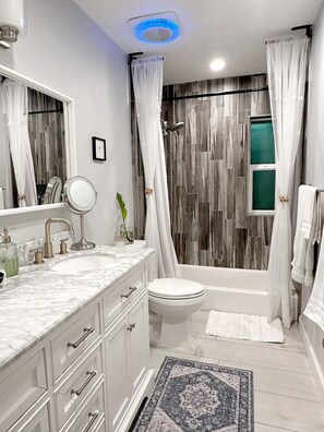 A modern bathroom with a marble sink, a toilet, and a bathtub. - Scottsdale Charm in Old Town (Scottsdale)