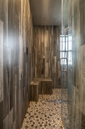 A modern shower area with a glass door, wooden steps, and a pebble-patterned floor. - Scottsdale Charm in Old Town (Scottsdale)