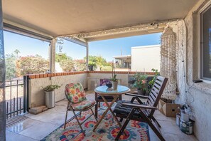 A covered outdoor seating area with a round table, two chairs, and a potted plant. - Scottsdale Charm in Old Town (Scottsdale)