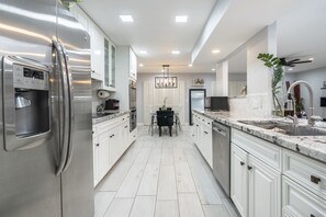 A modern kitchen with stainless steel appliances, white cabinetry, and a central island with seating.