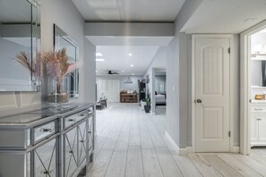 A modern kitchen with a central island, a dining area with a chandelier, and a hallway leading to a bedroom. - Scottsdale Charm in Old Town (Scottsdale)