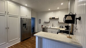 A kitchen with white cabinets, a stainless steel refrigerator, a sink, and a stove.