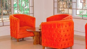 A room with two orange armchairs and a small wooden table. - Mkomazi Hotels and Campsite (Kisiwani)