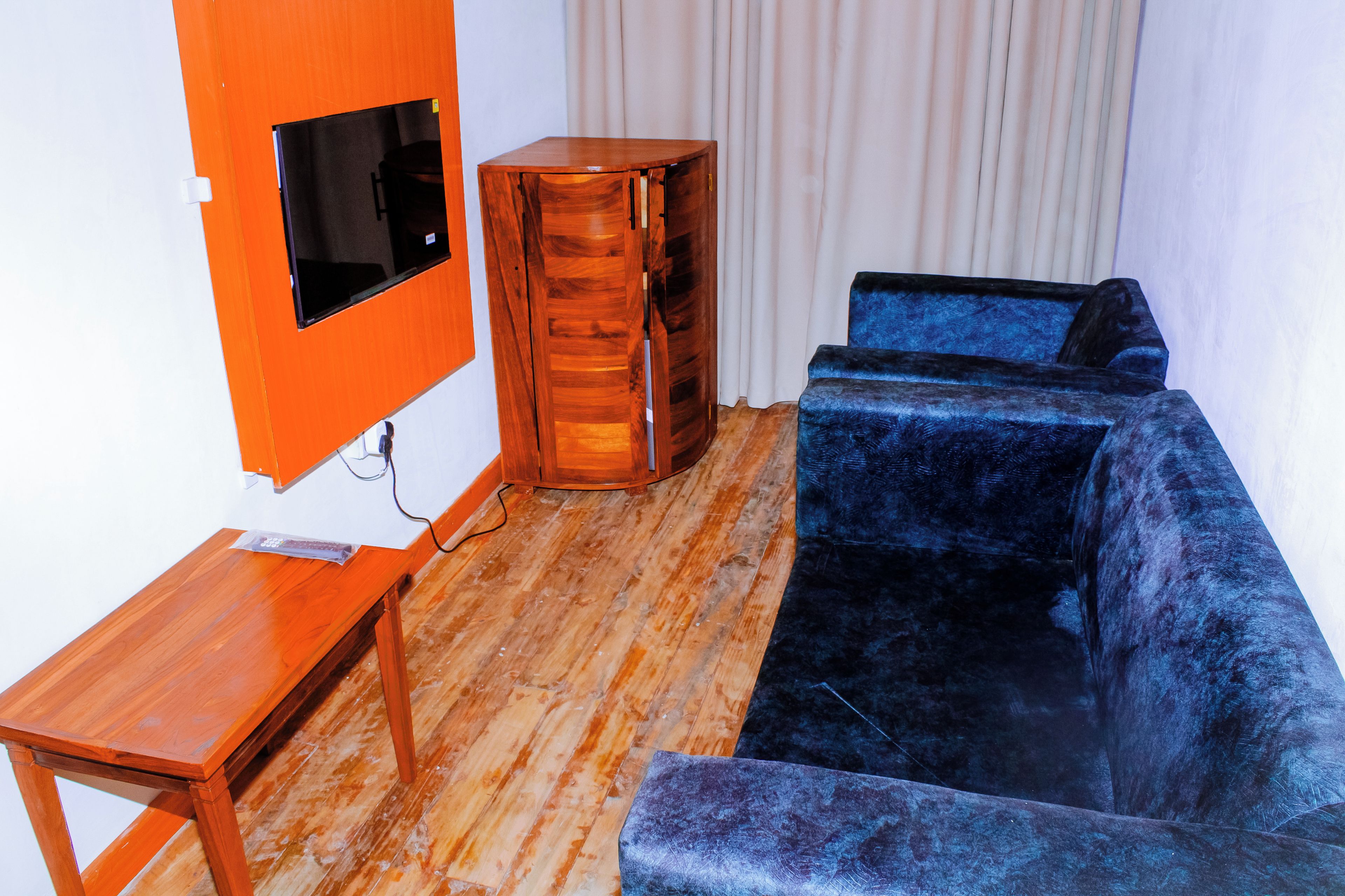 Una sala de estar con un mueble de televisión de madera, un sofá azul y un armario de madera.