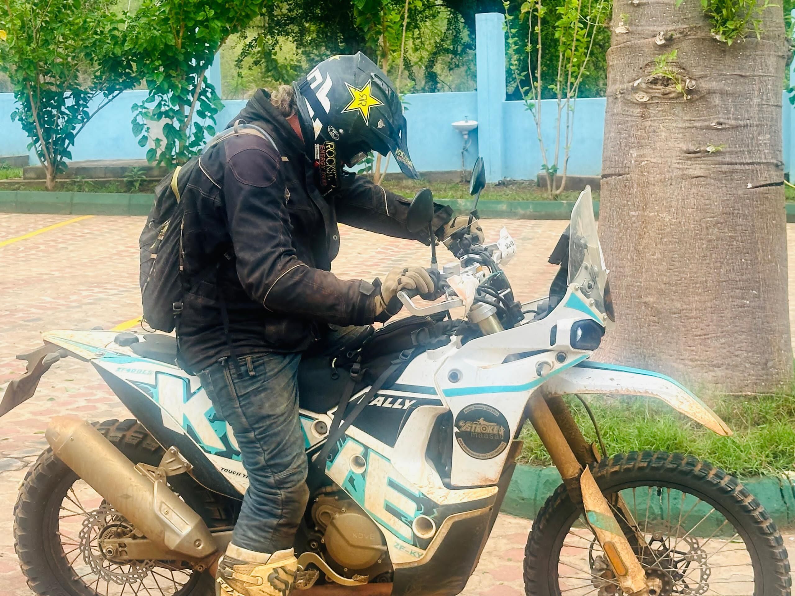 Une personne assise sur une moto, portant un casque et un sac à dos.