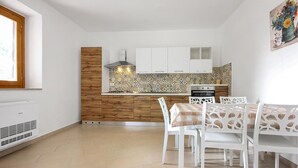 A compact kitchen with a wooden accent wall, white cabinets, and a patterned backsplash.