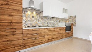 A modern kitchen with wooden cabinets, a gas stove, a built-in oven, and a patterned backsplash.