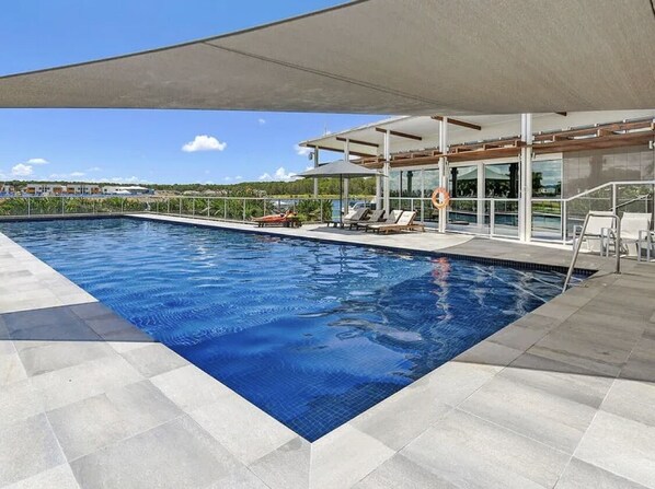 Relax by the pool surrounded by lounge chairs and umbrellas.