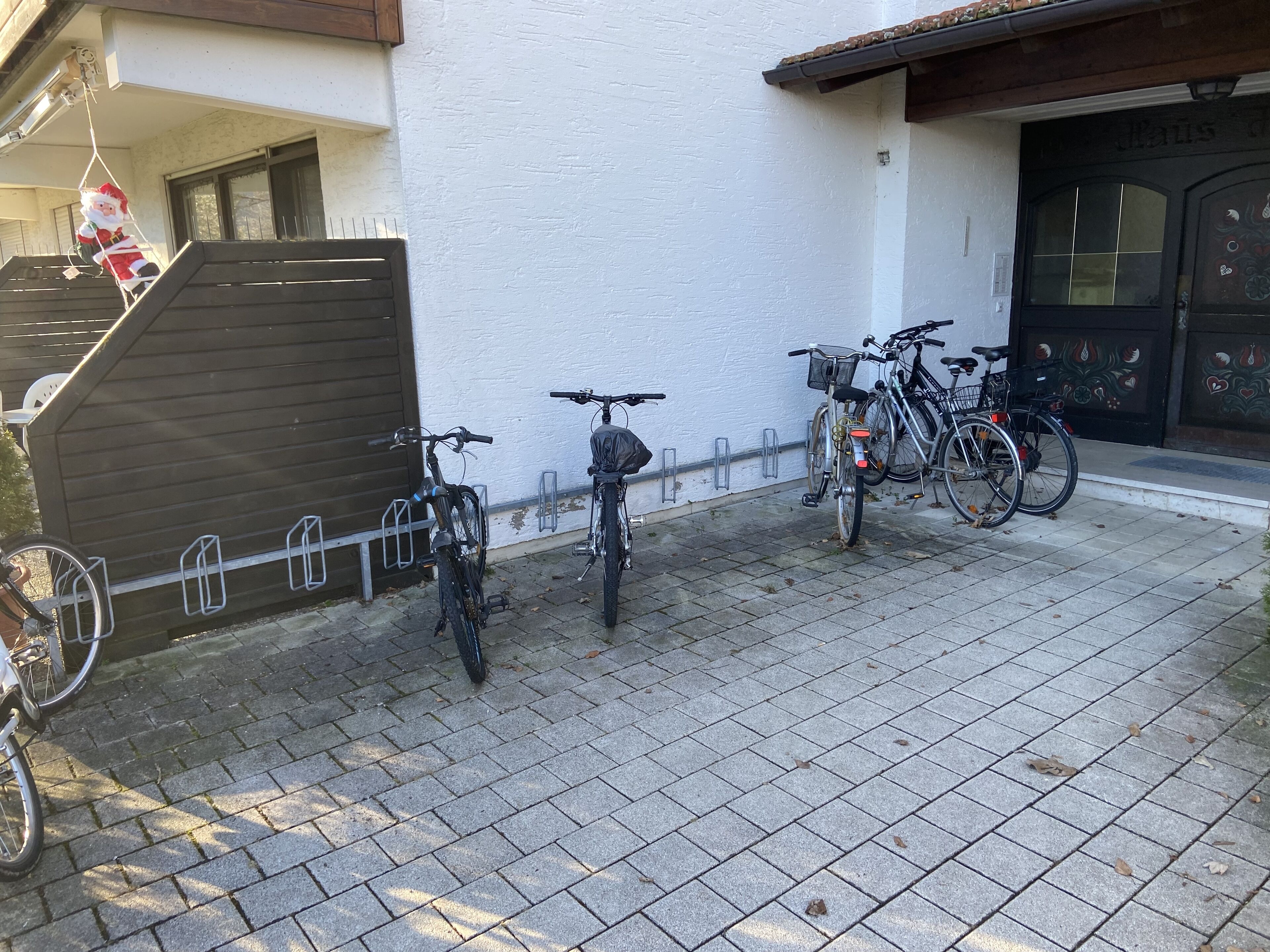 Un carrer pavimentat amb bicicletes aparcades al costat d'un edifici amb façana blanca i porta negra.