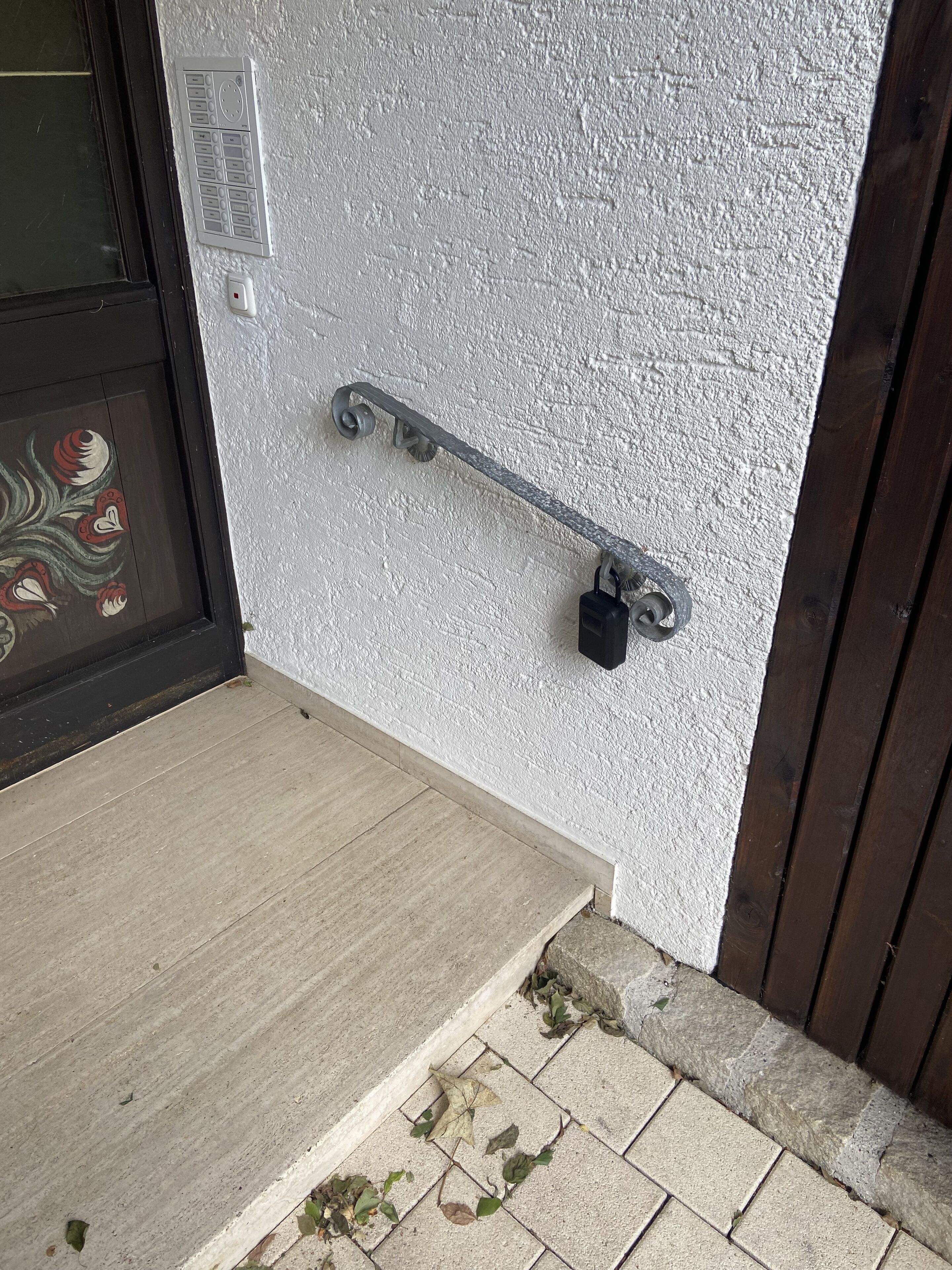 Una puerta con pared blanca texturizada, un picaporte metálico y un pequeño cerrojo.