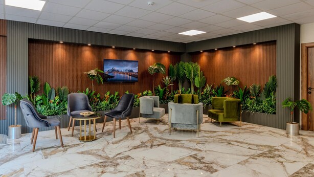 A lobby with a marble floor, several seating areas with modern chairs, a large flat-screen TV on the wall, and lush green plants. - The Business Class Hotel (Istanbul)